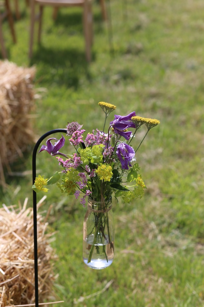 hanging bottle of flowers for pew ends in an outdoor wedding