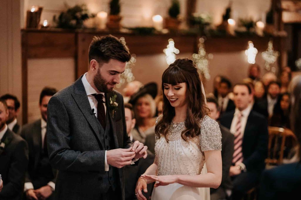 Groom puttin gwedding ring on brides finger at Pangdean barn wedding ceremony