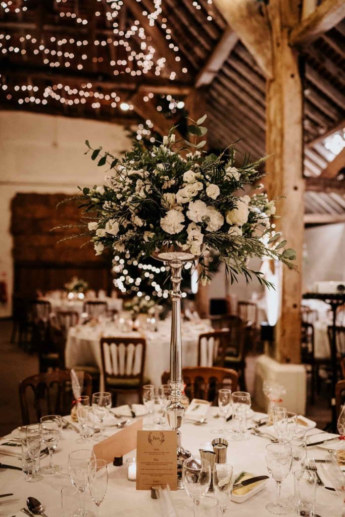 tall table centres of white flowers at Pangdean barn wedding reception